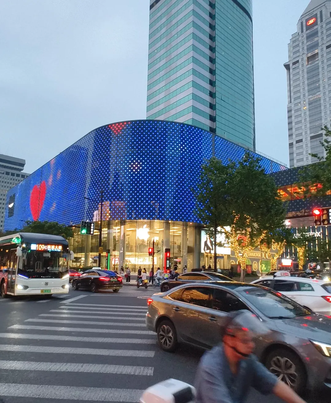 مبنى بواجهة LED منحنية زرقاء عند تقاطع في Nanjing Road، وحركة المرور في المقدمة